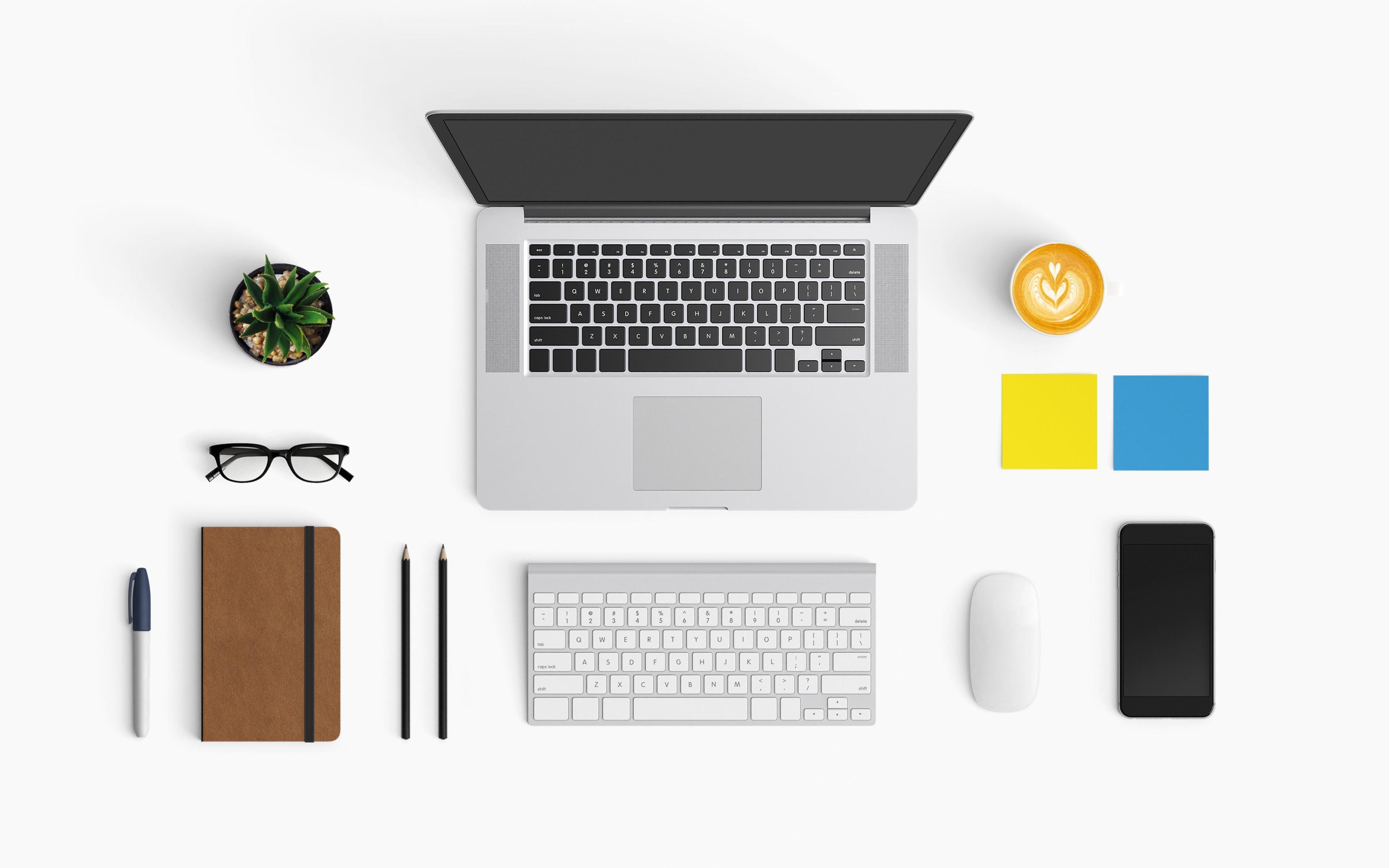 Un bureau avec un ordinateur portable, des ustensiles d'écriture, du café, des post-its